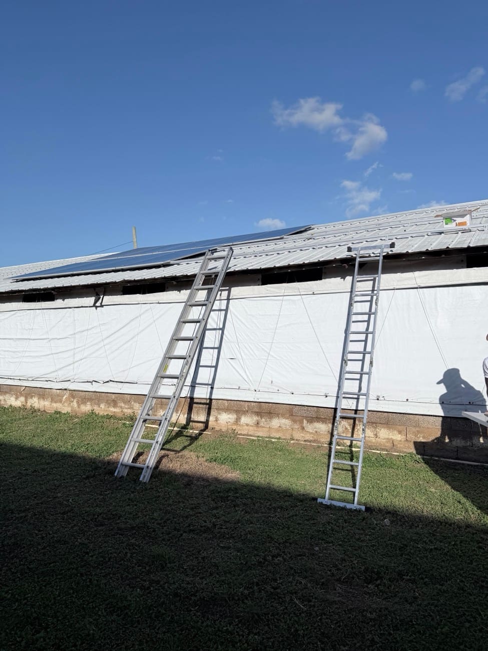 Ladders against the building with the first rows of panels already on the roof