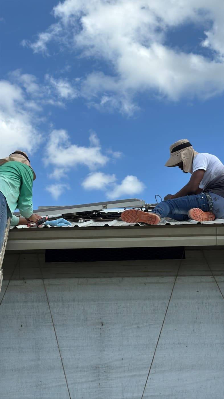 Two installers fixing mounting rail along the edge of a roof