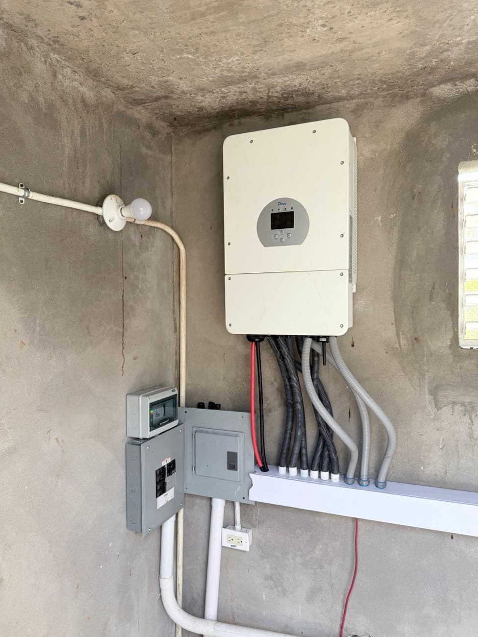 A Deye hybrid inverter wired into breaker panels through conduit